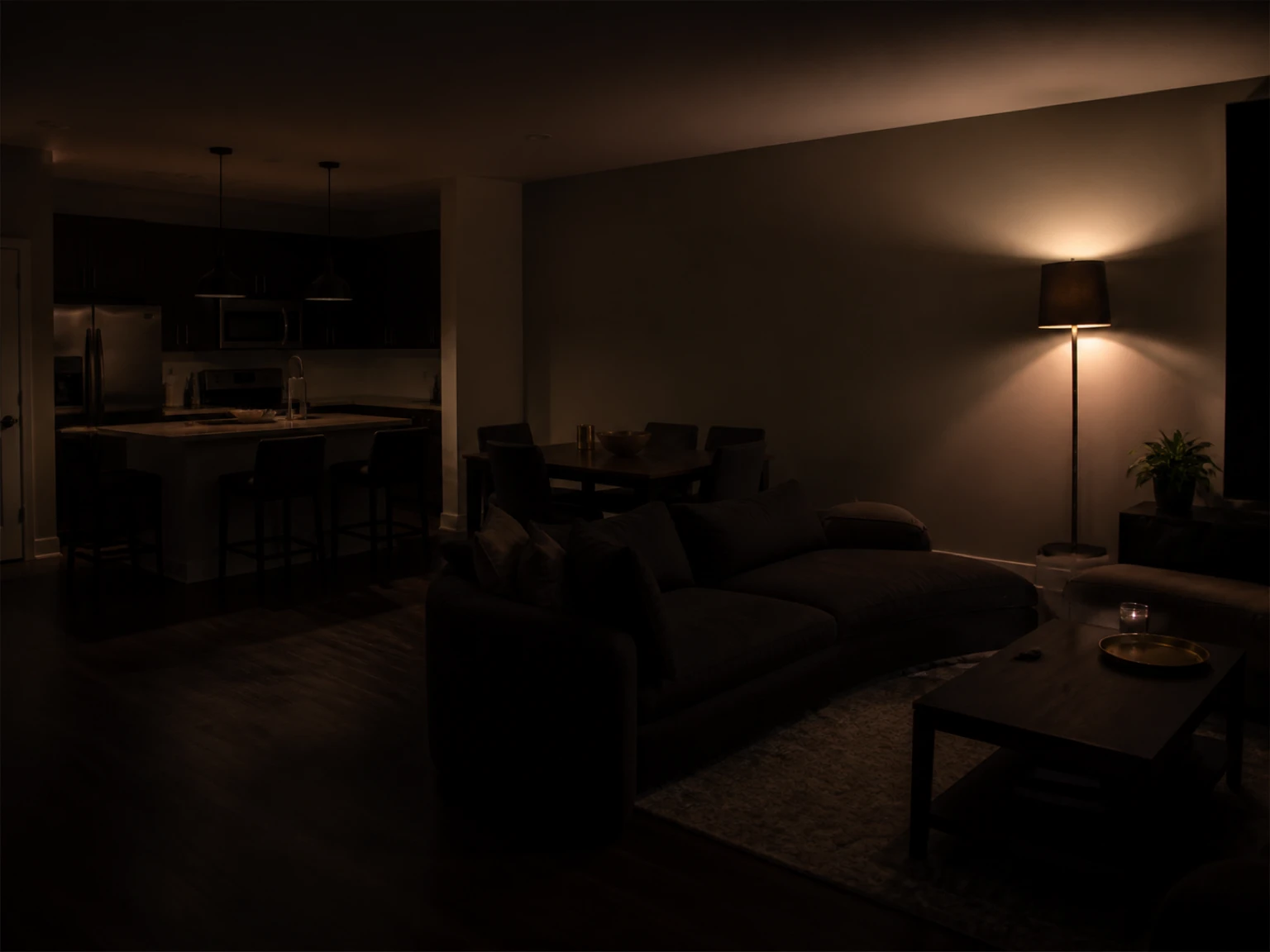 Large open living room with a tall floor lamp spreading warm light across a broad wall