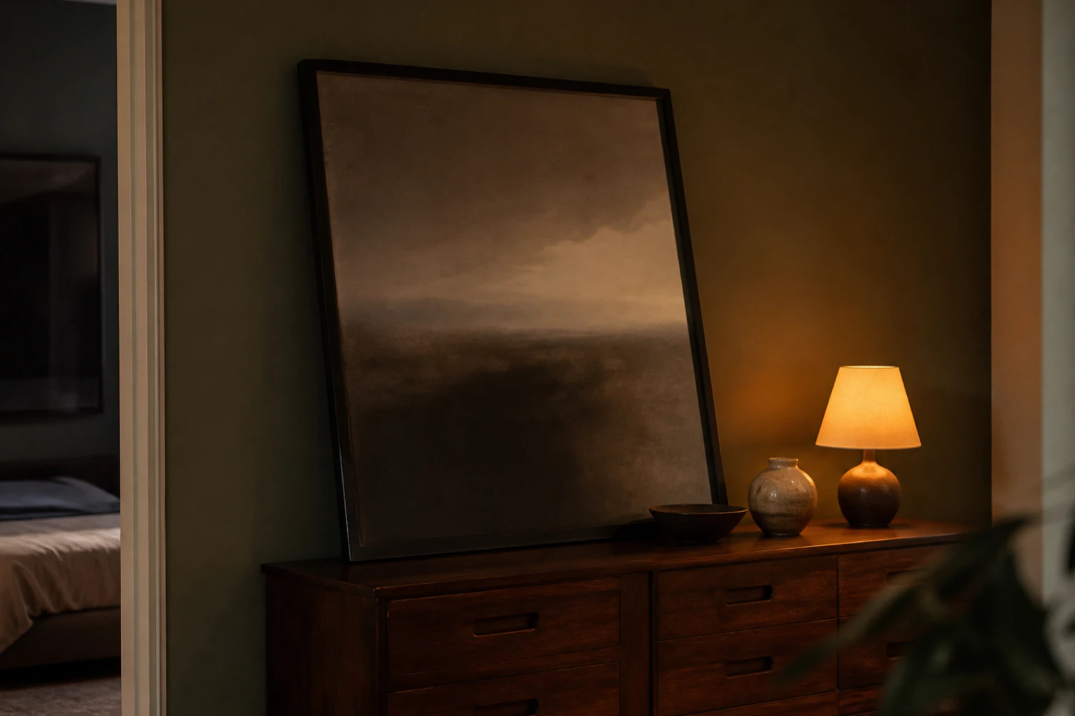 Large framed artwork leaning against a wall on top of a low dresser