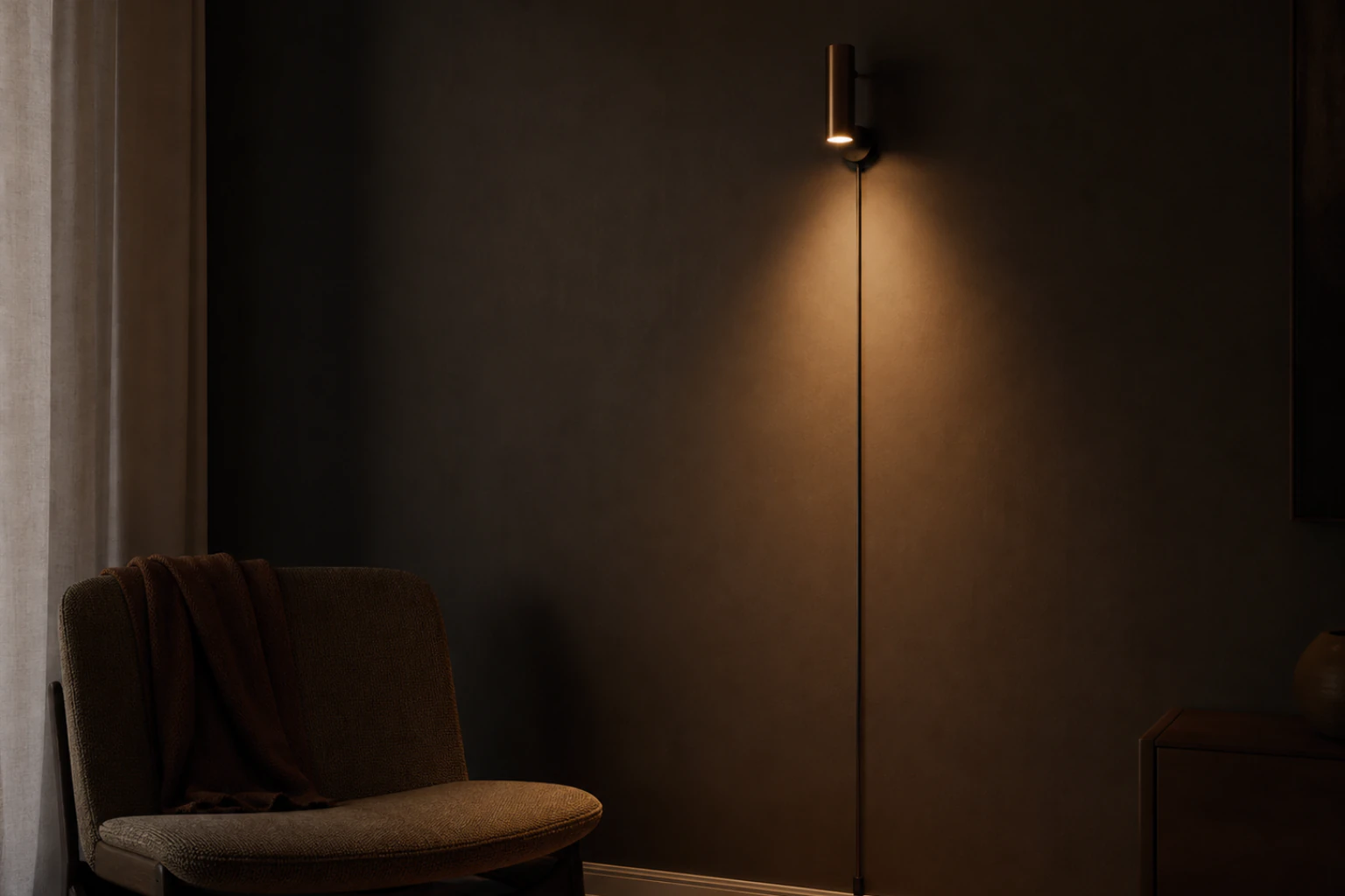 Warm plug-in sconce mounted on a dark rental wall with a tidy cord route